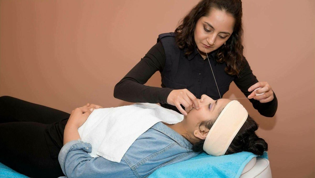 A Lahana team member carrying out an eyebrow threading treatment in the salon